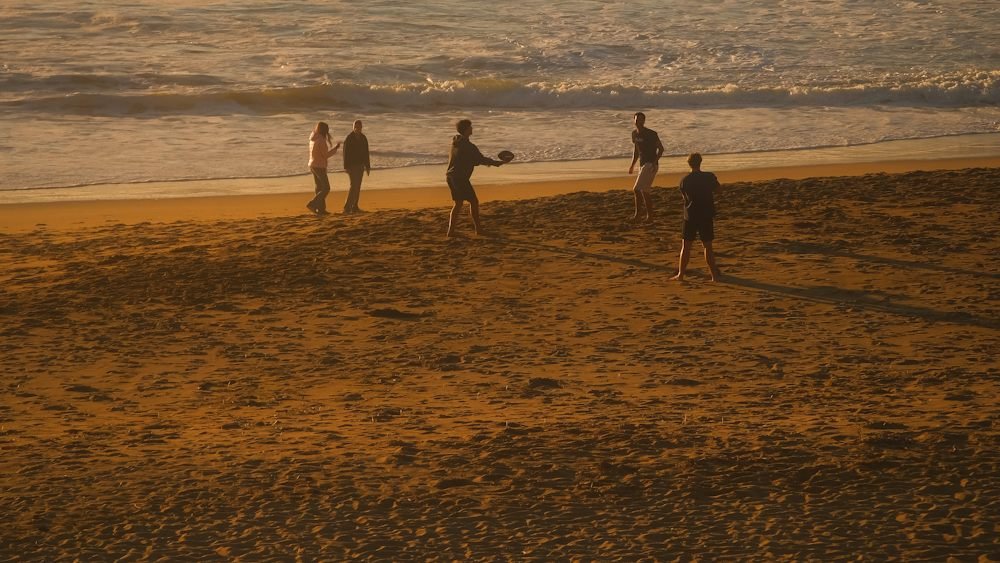 Friends enjoying a sandy beach at sunset, ideal for summer group and family travel in June