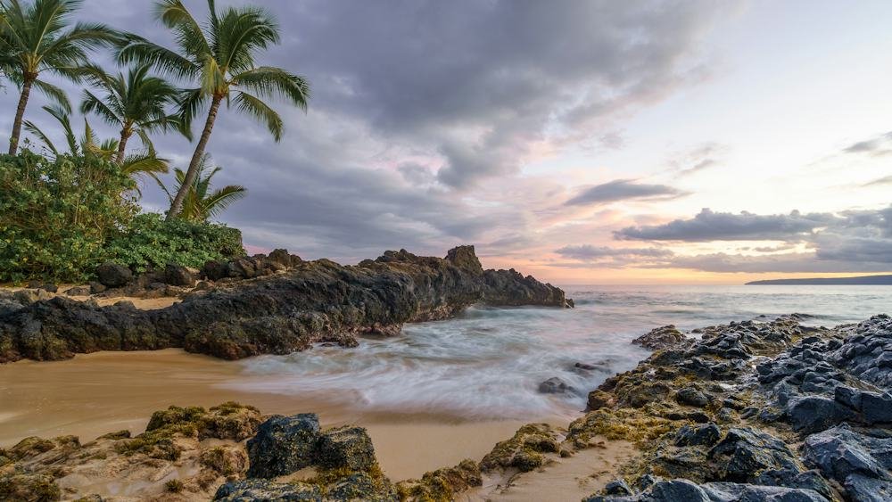 Secret beach on Maui with volcanic rock and lush cliffs, a top tropical destination in July