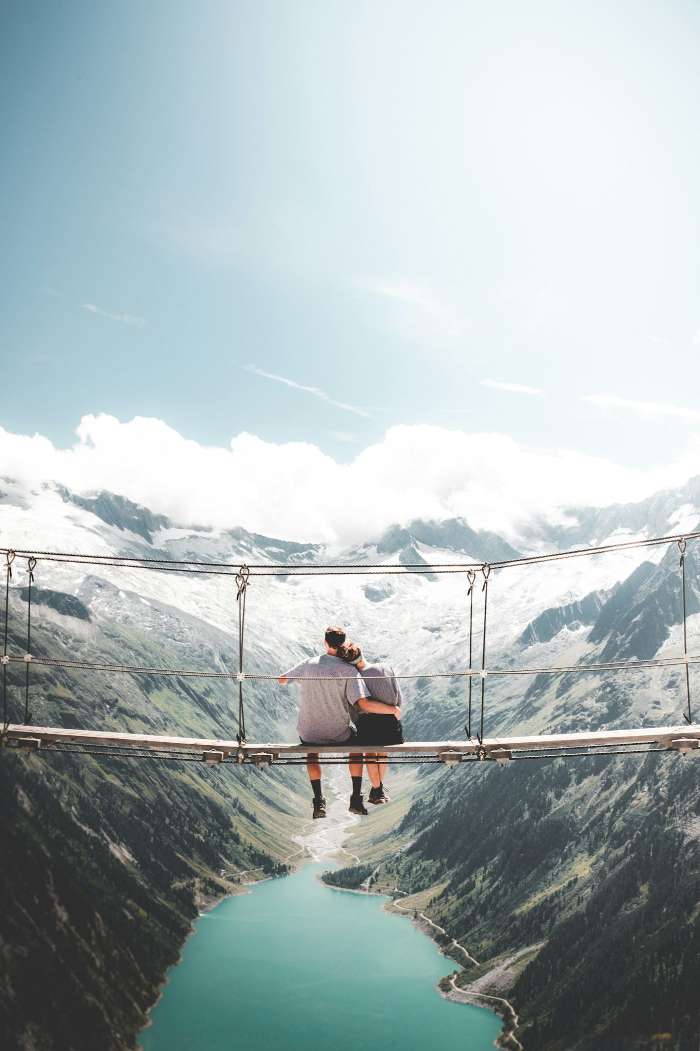 Couple sitting together on a hanging bridge during a scenic daytime activity on their weekend trip