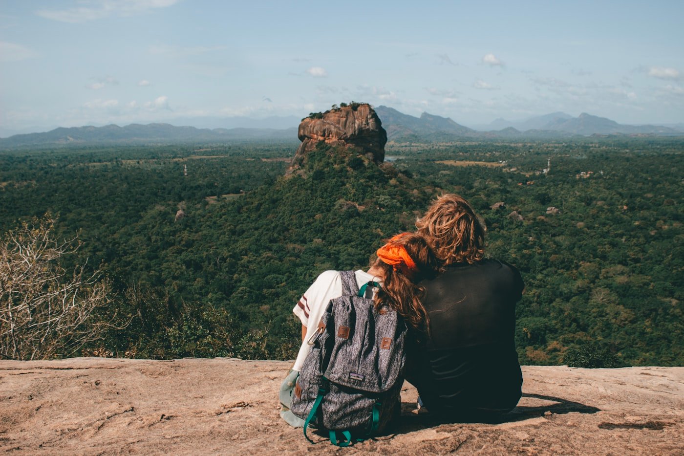 Couple sitting beside a scenic cliff enjoying a luxury weekend getaway view