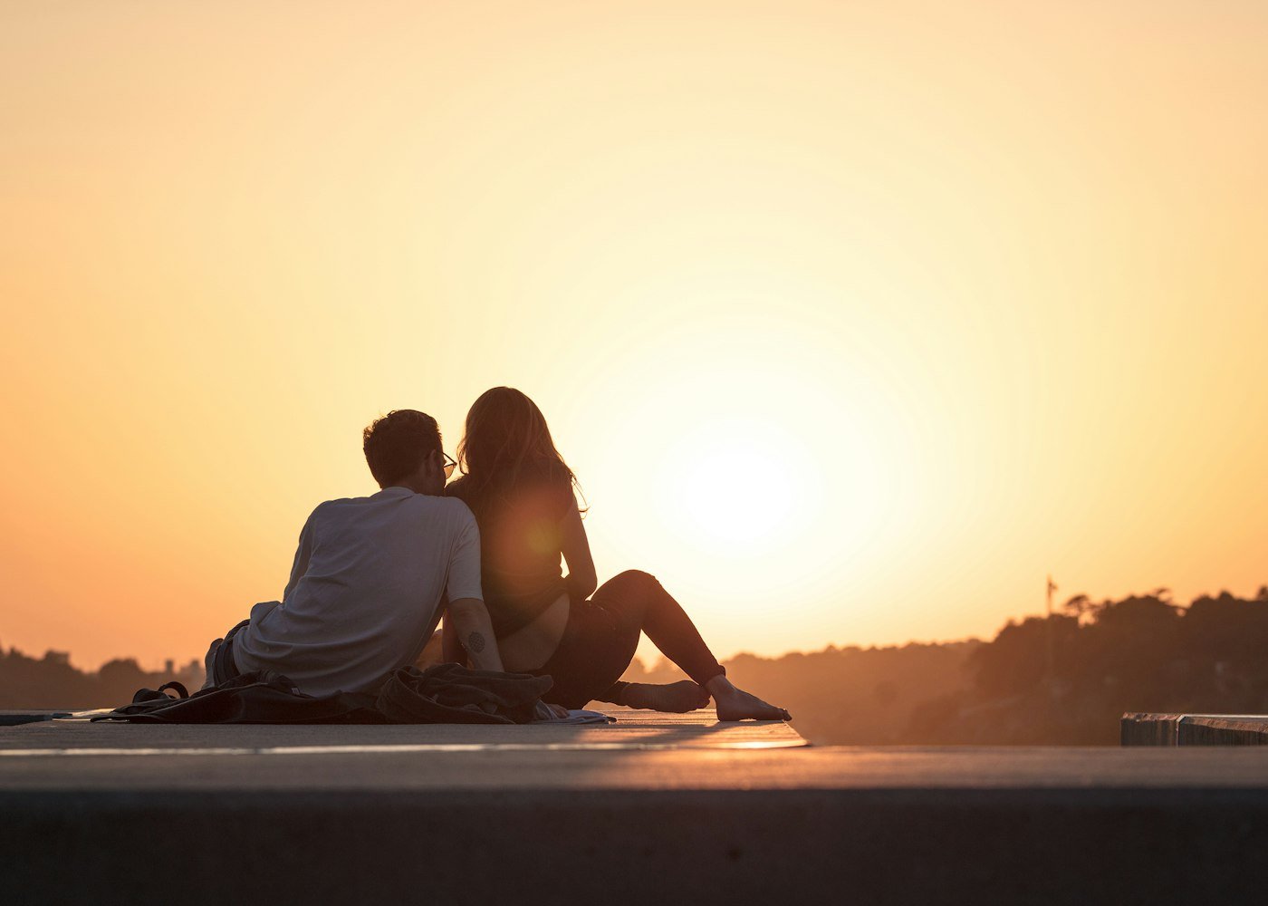 Couple sitting near trees during golden hour on a mountain honeymoon getaway